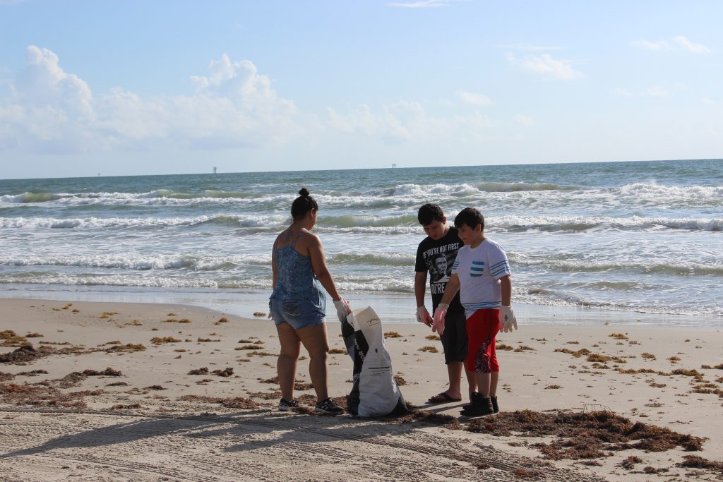 Family removing trash from corpus christi beach